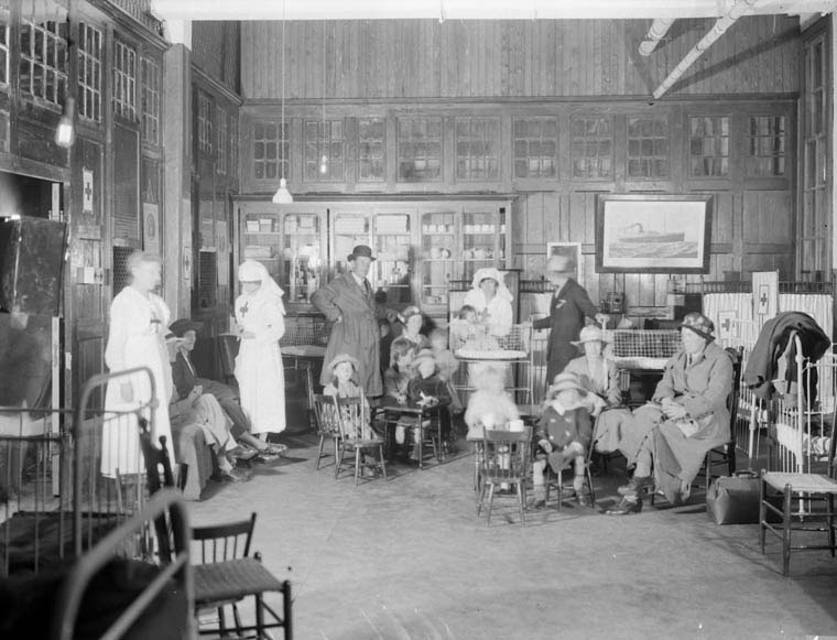 While waiting to entrain [board trains] to their final destinations, new arrivals with babies and children could spend time in the Red Cross Room at the Immigration Hall in Quebec.